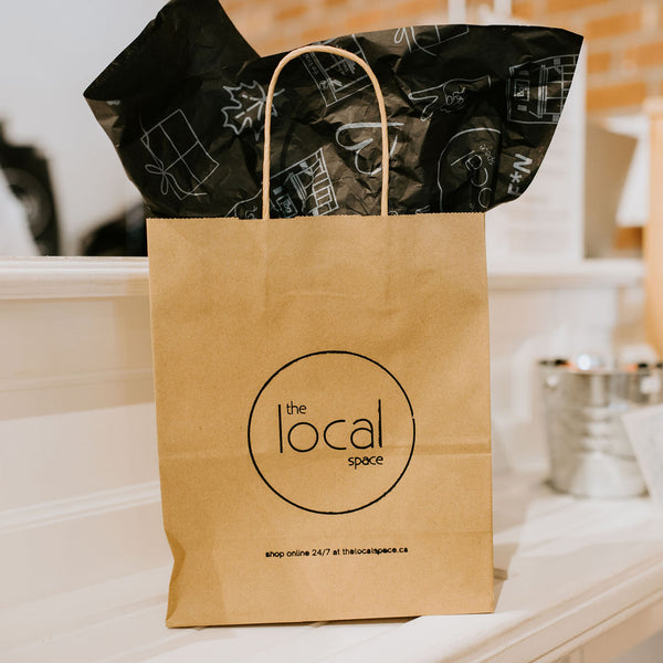 Kraft gift bag with The Local Space logo and black tissue paper